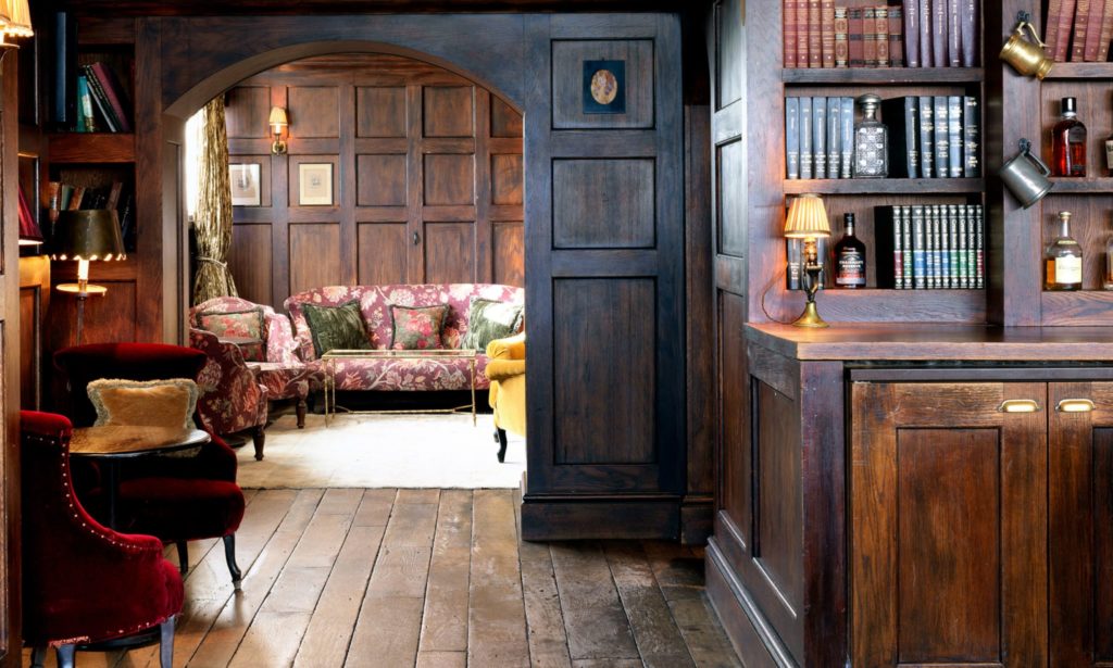 a look into the library area at electric house, with books behind the bar and plush armchairs and sofas dotted around