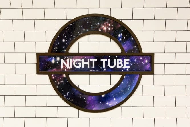 A London Underground roundel decorated with a starry night and the words 'Night Tube'