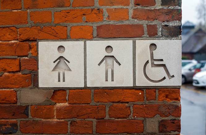 Public toilet street sign with male, female and disabled people icons on it.