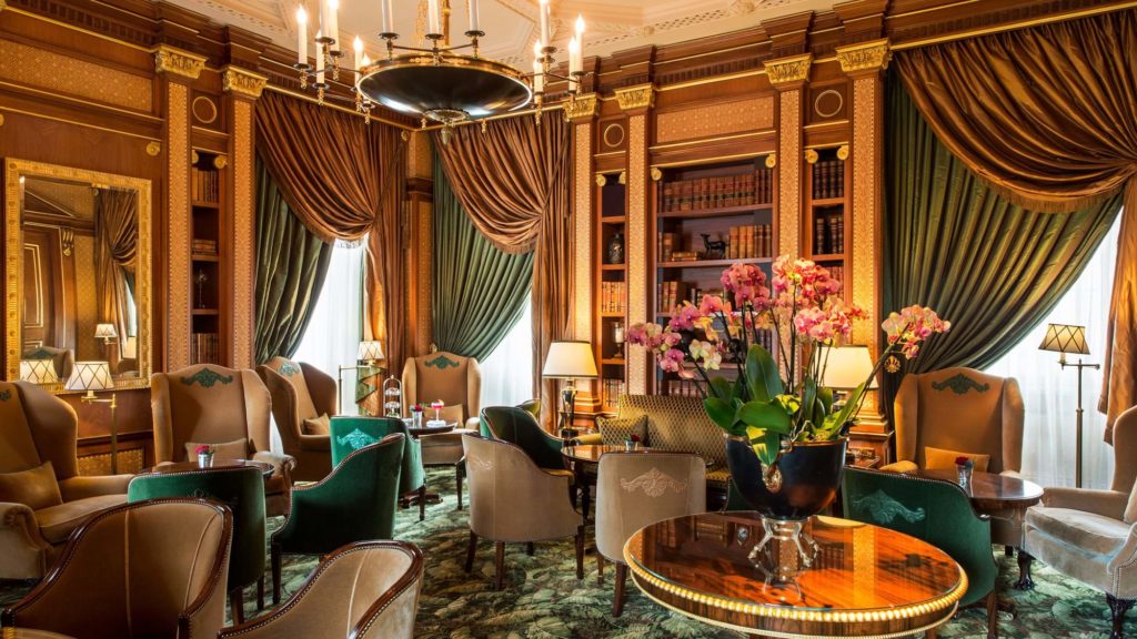 the plus interiors of the lanesborough's library bar showing luxurious seating and shelves packed with books