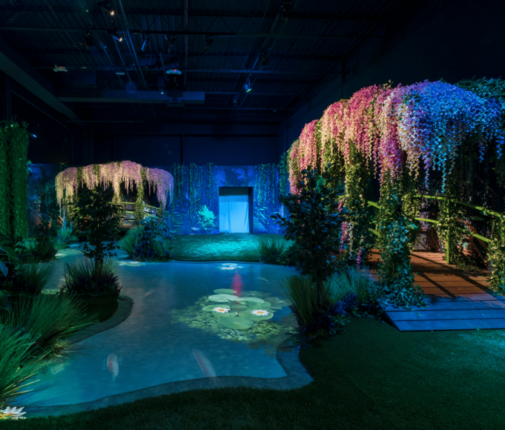 footbridges draped with loads of flowers lead over a digital pond with fish and lilies